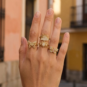 Close-up of four gold butterfly and sun rings with zircons on a hand in natural light