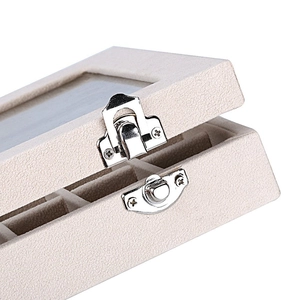 Macro shot of silver metal latch and beige velvet texture on small jewelry box with window