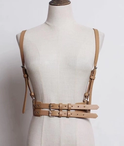 Detail of beige faux leather harness corset belt with double straps and metallic buckles