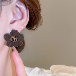 Close-up of vintage fabric flower earrings with leopard print bead on model ear