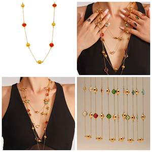 Détail d'un long collier doré orné de pierres en verre coloré et chaîne perlée