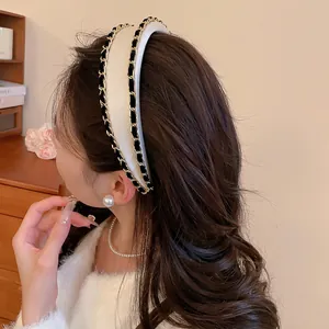 Fashionable white fabric headband with gold chain trim on a model in a cozy indoor setting