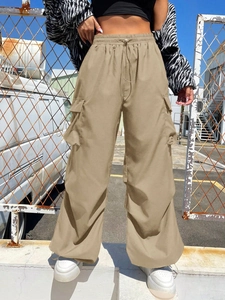 Detail of khaki cargo pants featuring drawstring waist and large flap side pockets on street