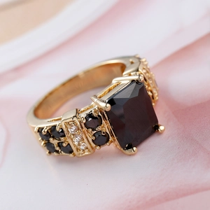 Macro shot of gold vintage ring featuring a rectangular black gemstone and side zircon accents