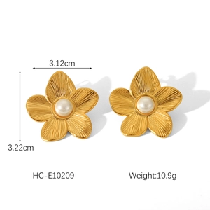 Detail view of 18K gold flower earrings with white pearl and brushed metal texture