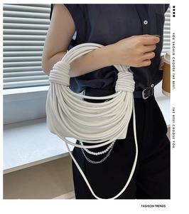 Dettaglio macro della borsa a mano bianca intrecciata con catena di perle e design trendy