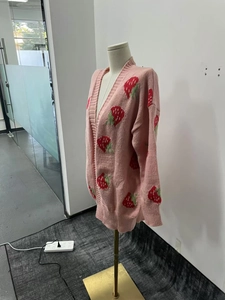Close-up of pink V-neck knit cardigan with cute strawberry patterns and button details