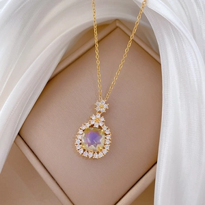 Detailed shot of golden flower pendant featuring a rainbow faceted stone and diamonds