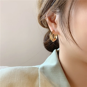 Close-up of a double-layered gold geometric hoop earring worn on a model's ear