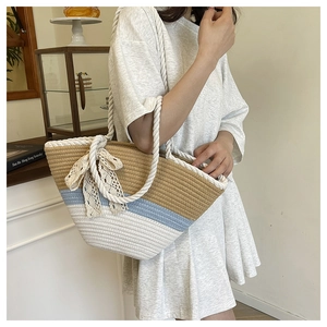 Détail du sac seau tissé à rayures avec des accents de nœuds en dentelle marron et bleu