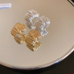 Minimalist C-shaped metal hoop earrings in gold and silver with pleated texture