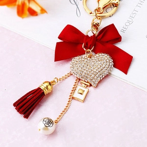 Detailed close-up of a red bow and rhinestone heart keychain with a camellia pearl charm