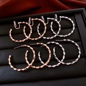 Detail of rose gold and silver geometric hammered hoop earrings on black tray