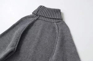 Close-up of grey chunky knit sweater showing rib-knit high collar and raglan sleeve texture