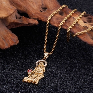 Close-up of gold religious shepherd pendant with red gemstone on black textured wood