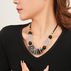 Close-up of leather cord necklace with large black, grey, and white resin stone beads