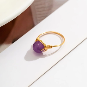 Detailed macro shot of handmade gold wire-wrapped ring with a purple amethyst gemstone
