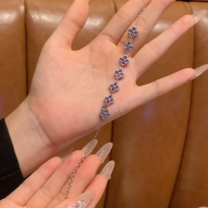 Detail of silver chain bracelet with seven purple cubic zirconia flower charms