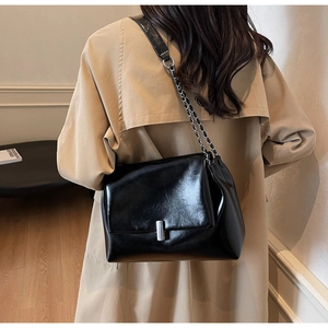 Detail of a black vintage crossbody bag featuring a silver metal lock and chain strap