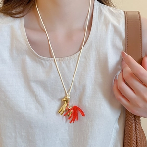 Detail of golden horse pendant with red crystal tail tassel on minimalist cord