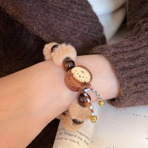 Gros plan d'un bracelet mignon avec pompon en peluche, perles en bois et pendentif