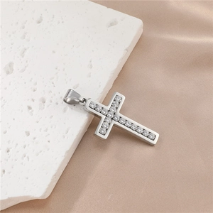 Détail d'un pendentif croix en acier titane avec diamants sur pierre blanche