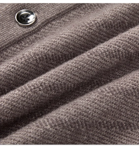 Makroansicht der dunkelbraunen Stricktextur und des glänzenden Harzknopfs an der Weste