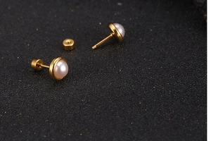 Macro detail of gold vintage pearl stud earrings with secure screw-back closures