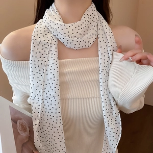 Detail of a white neck scarf with black polka dots on a model in soft lighting