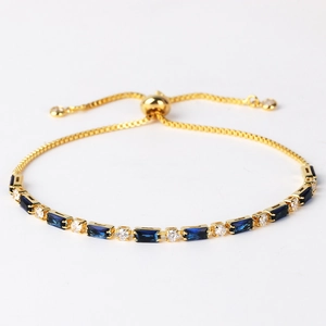 Detail of gold snake chain bracelet with dark blue rectangular and clear round stones