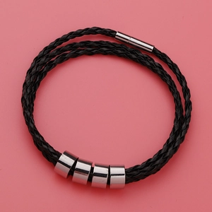 Detailed close-up of a black braided leather bracelet with four silver metal spacers