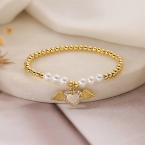 Detail view of heart-shaped wing charm with cubic zirconia on a beaded pearl bracelet