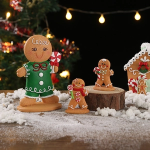 Christmas gingerbread man figurines with a festive house on a wooden base in warm lighting