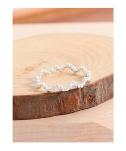 Macro shot of twisted wave silver ring on natural wood texture with polished metal detail