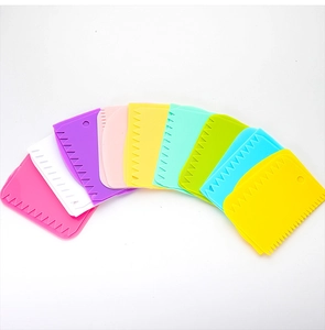 Flat lay of colorful plastic cake scrapers with serrated edges on a white background