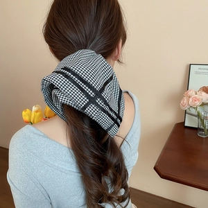 Close-up of a vintage black and white checkered hair scrunchie styled on a low ponytail