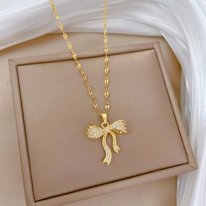 Elegant gold bow necklace with sparkling cubic zirconia on a luxury jewelry box
