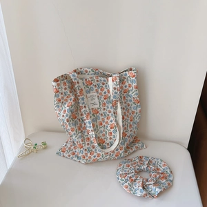 Close-up of floral cotton tote bag set with matching scrunchie and golden bow hair claw