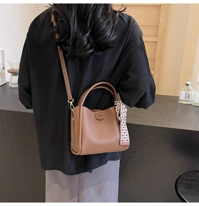 Close-up of brown lychee grain leather bucket bag with decorative checkered scarf