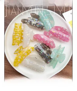Close-up of colorful acetate hair claws with artistic oil painting patterns in a tray