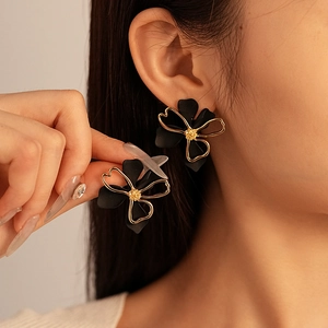 Elegant double-layered black petal stud earrings with gold edges worn by a model