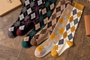 Flat lay of five vintage argyle knee-high socks in assorted colors on wooden floor