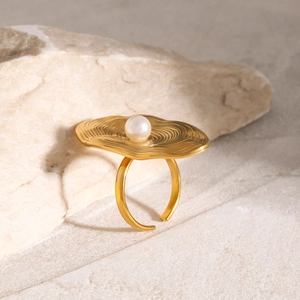 Macro shot of 18K gold plated pearl ring with irregular ripple texture on stone background