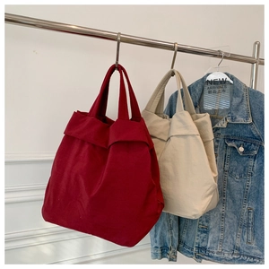 Detail view of burgundy and cream oversized tote bags with unique pleat design