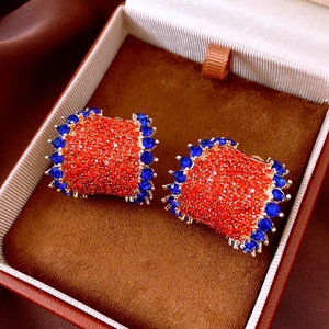 Macro shot of vintage C-shape earrings with orange pavé stones and blue crystals