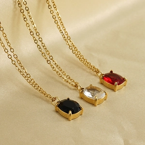 Macro detail of oval gemstone pendants in black, white, and wine red on gold necklaces