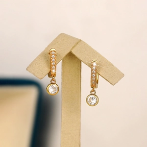 Macro detail of gold hoop earrings with sparkling cubic zirconia on a T-bar display