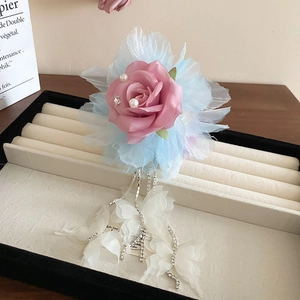 Détail de la pince à cheveux avec fleur en dentelle rose, franges et papillons blancs