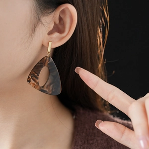 Close-up of leopard print resin earrings worn by a model in a retro style
