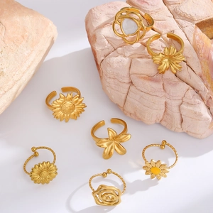 Macro detail of various gold-plated flower rings including sunflower and rose designs